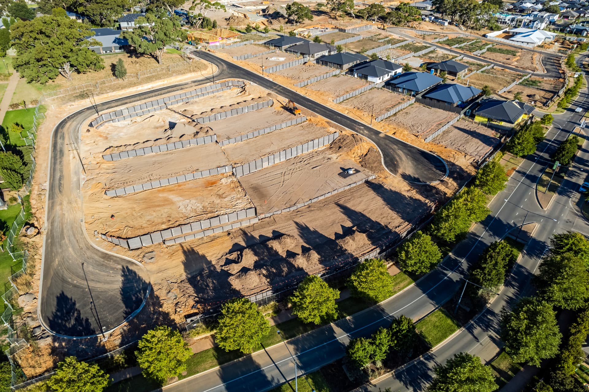 Aerial view of a residential subdivision with tiered precast concrete retaining walls under construction